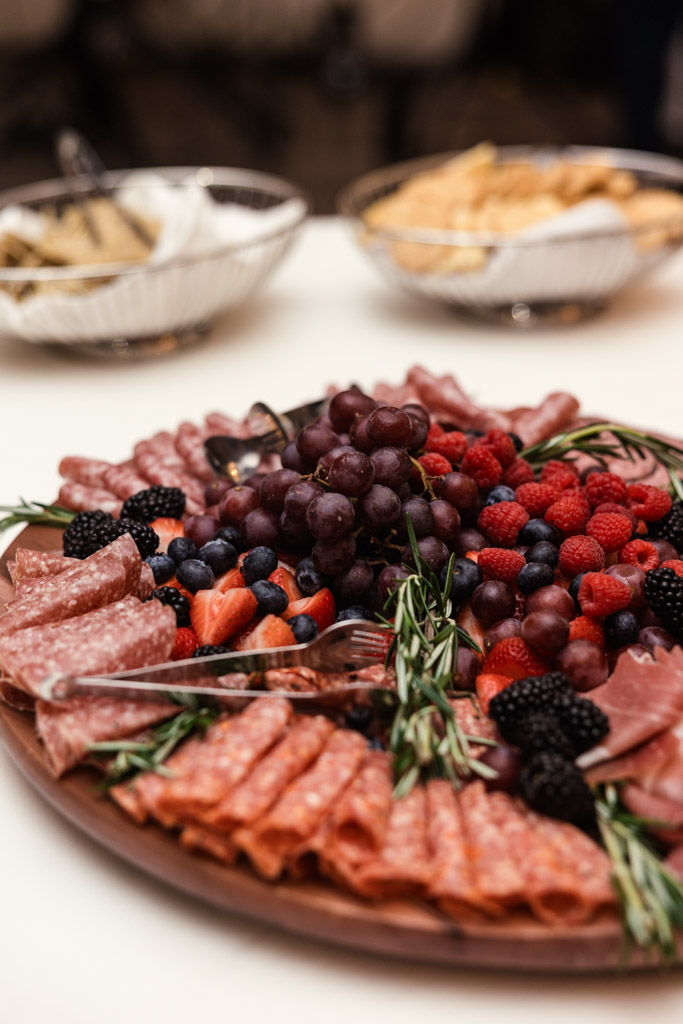 Salvatore's charcuterie board features assorted meats, berries, grapes, and rosemary, with other appetizers in bowls in the background