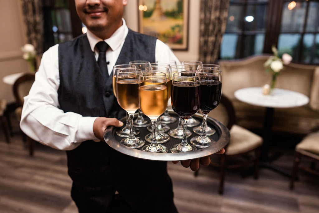A server at Salvatore's holds a tray of wine glasses filled with wine