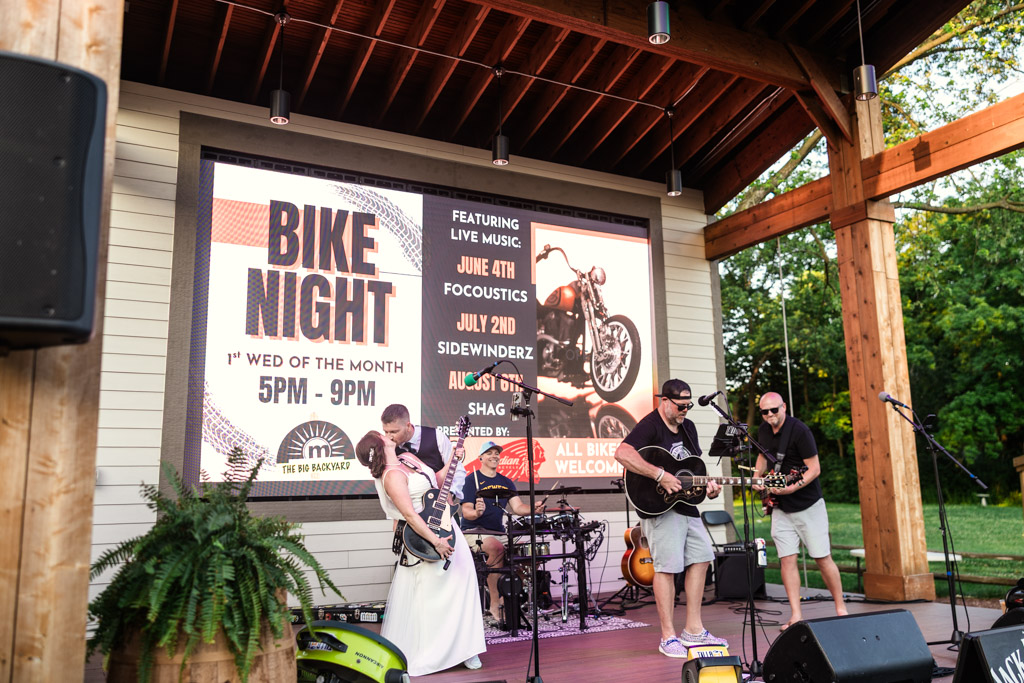 Newlyweds on stage with a band performing live during their Wisconsin summer wedding reception