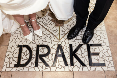 Bride and groom stand on mosaic tiles spelling "DRAKE," at The Drake Oakbrook
