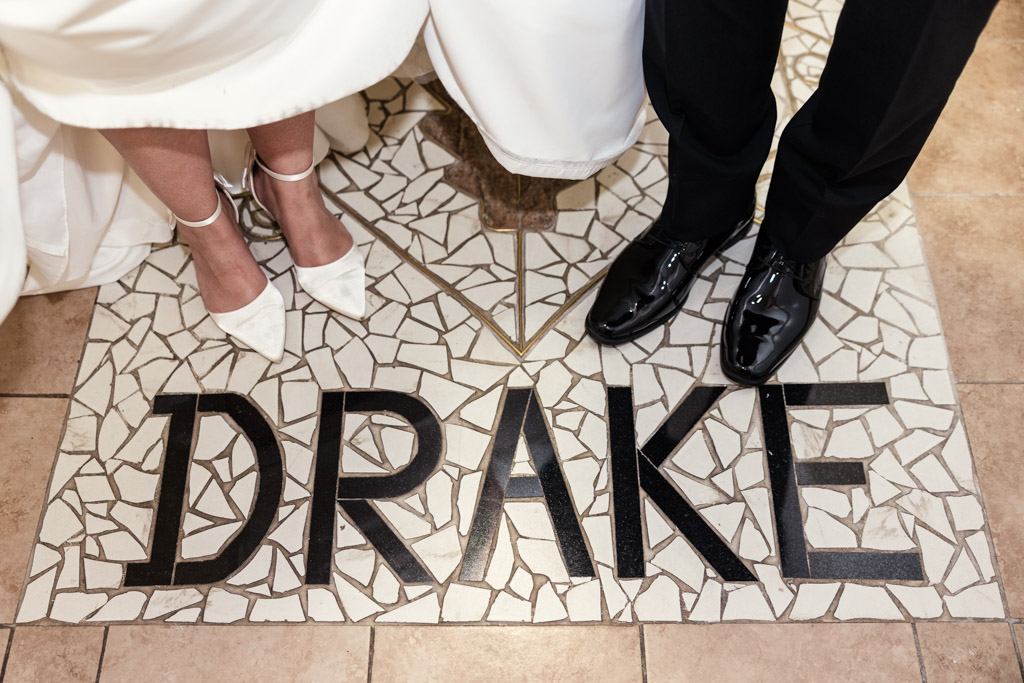 Bride and groom stand on mosaic tiles spelling 