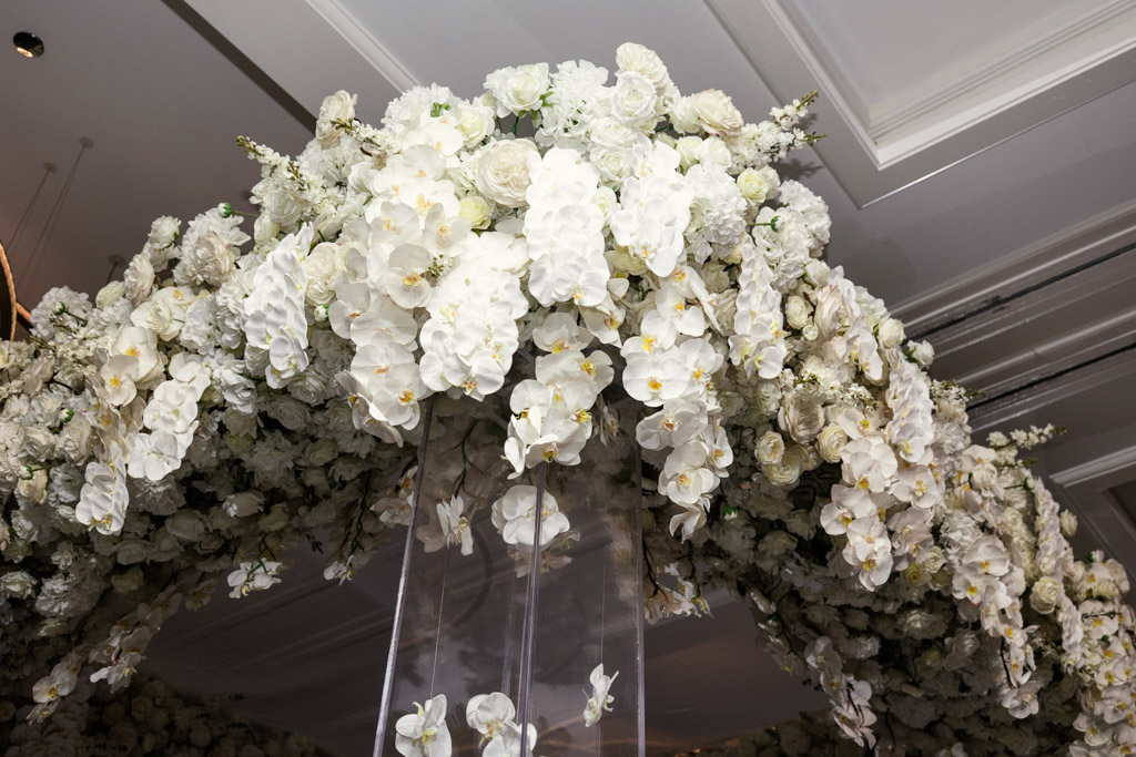 Detail photo of floral arch covered in white flowers, including orchids and roses for wedding ceremony at The Four Seasons Chicago