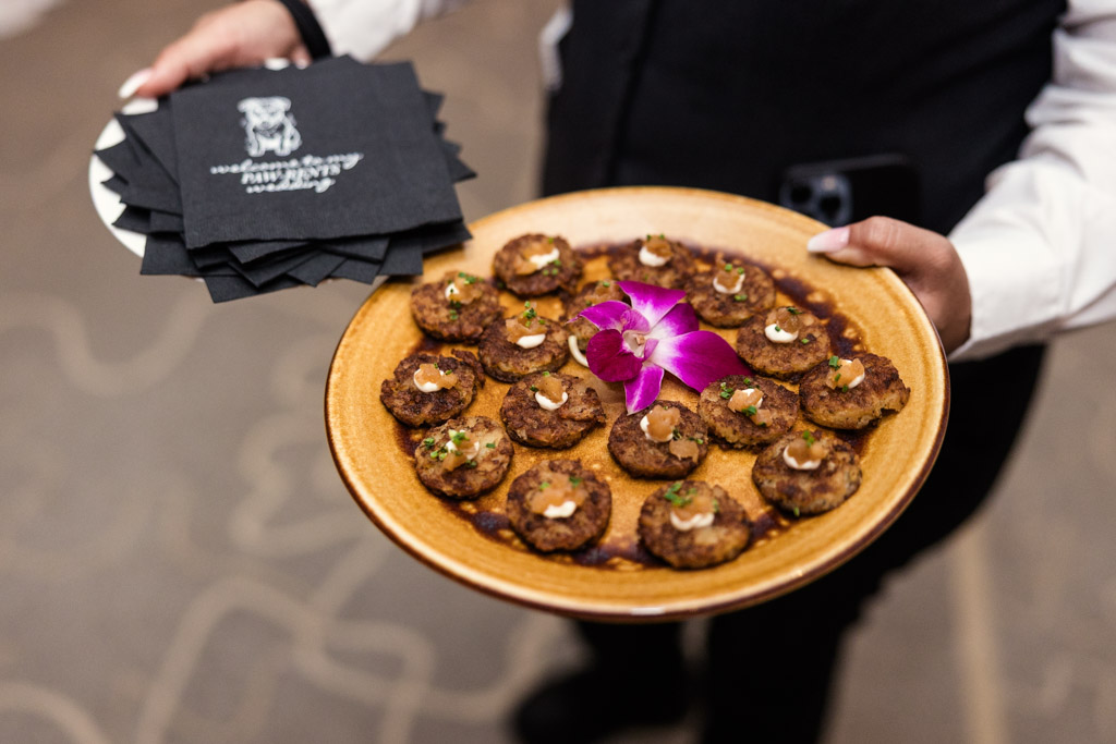 Plate of bite-sized appetizers garnished with an orchid, alongside black napkins for Four Seasons Chicago wedding reception