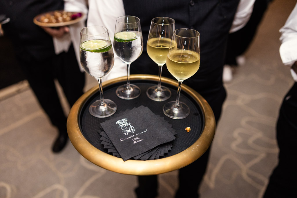 A server holds a tray with wine, water with lime, and black napkins at Four Seasons Chicago wedding reception