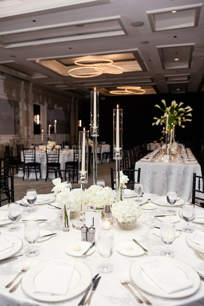 Round guest table with white linens, floral centerpieces, and tall candle holders for wedding reception at The Four Seasons Chicago