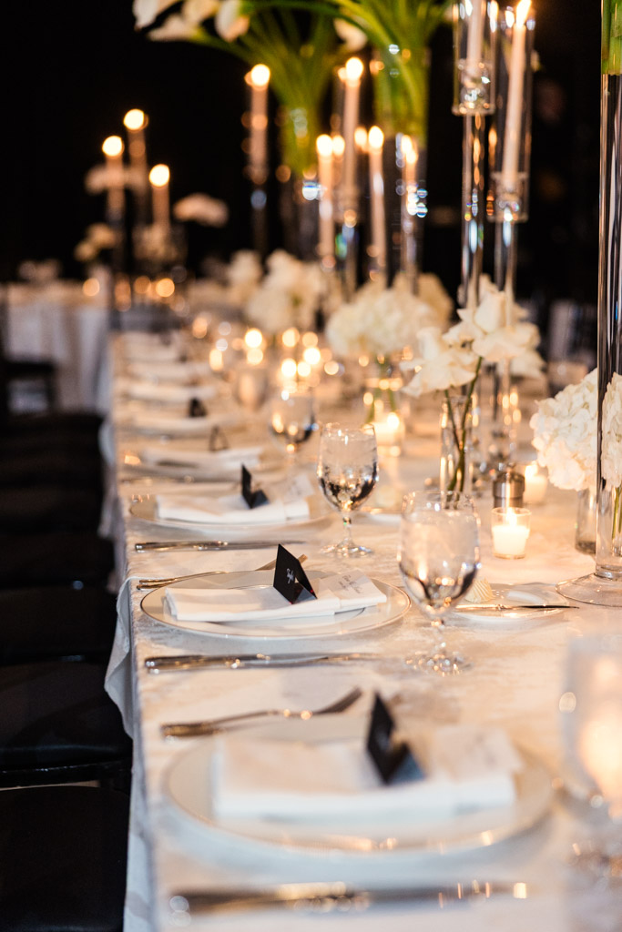Guest table set with white linens, glassware, candles, and white floral centerpieces creates a sophisticated atmosphere for wedding reception at The Four Seasons Chicago