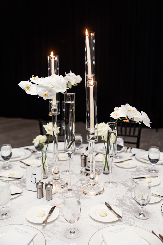 Guest table setting at The Four Seasons Chicago, featuring white flowers, tall glass candle holders, and neatly arranged dinnerware