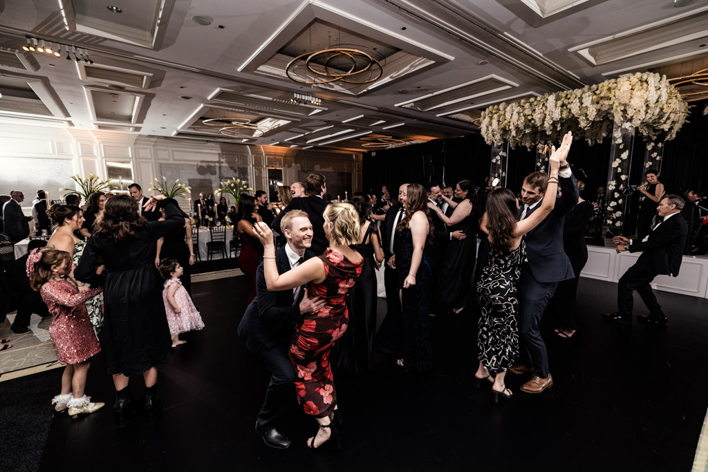 Guests dressed formally dancing and celebrating on a black dance floor during wedding reception at The Four Seasons Chicago