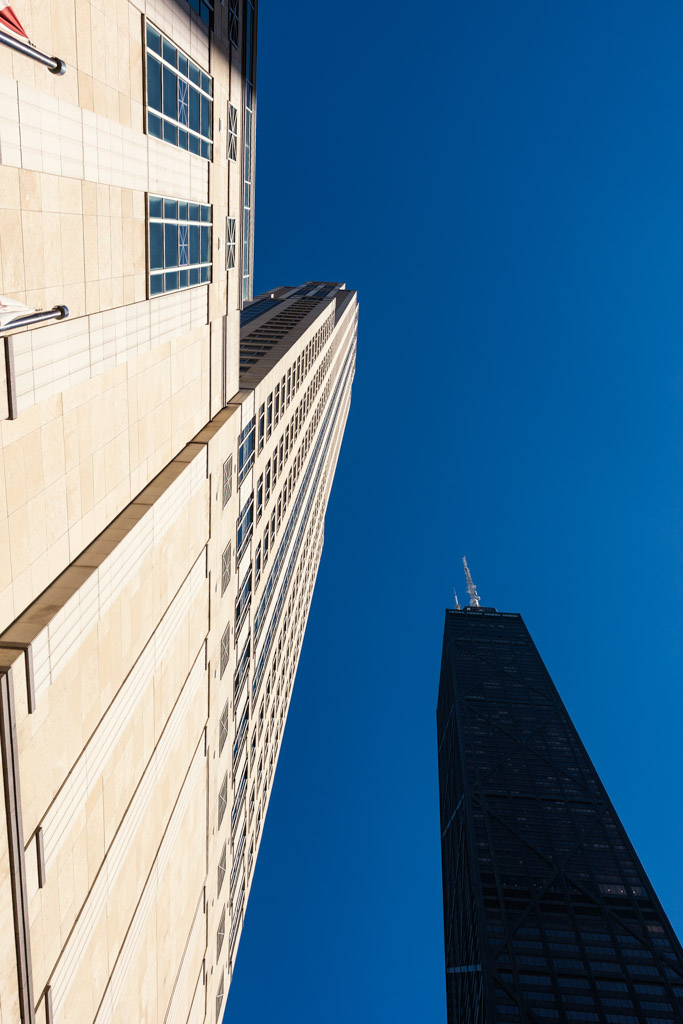 Upward view of Four Seasons Chicago and the John Hancock Building against a clear blue sky