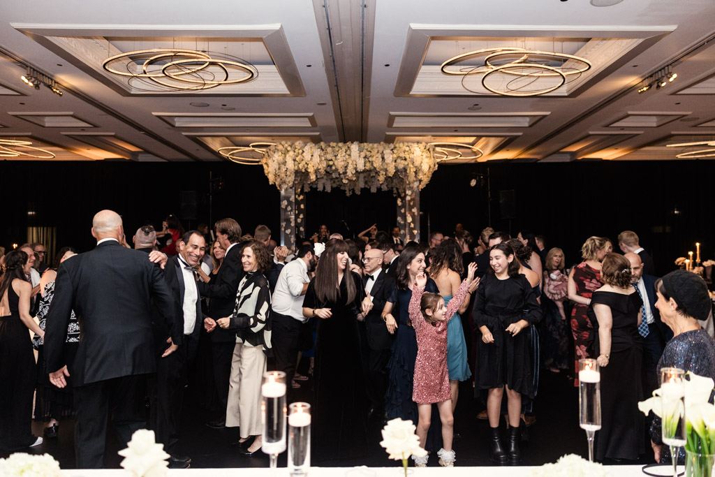 A large group of guests dance and celebrate together in the wedding reception space at The Four Seasons Chicago