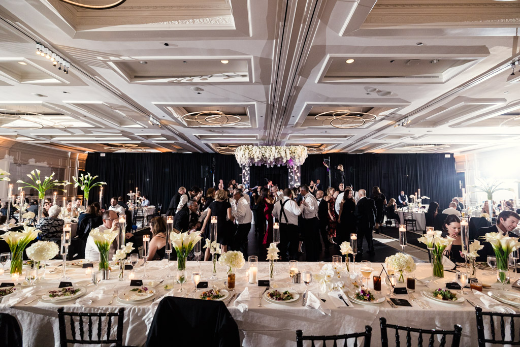 Wedding reception space at The Four Seasons Chicago with guests dining and dancing, featuring white floral centerpieces