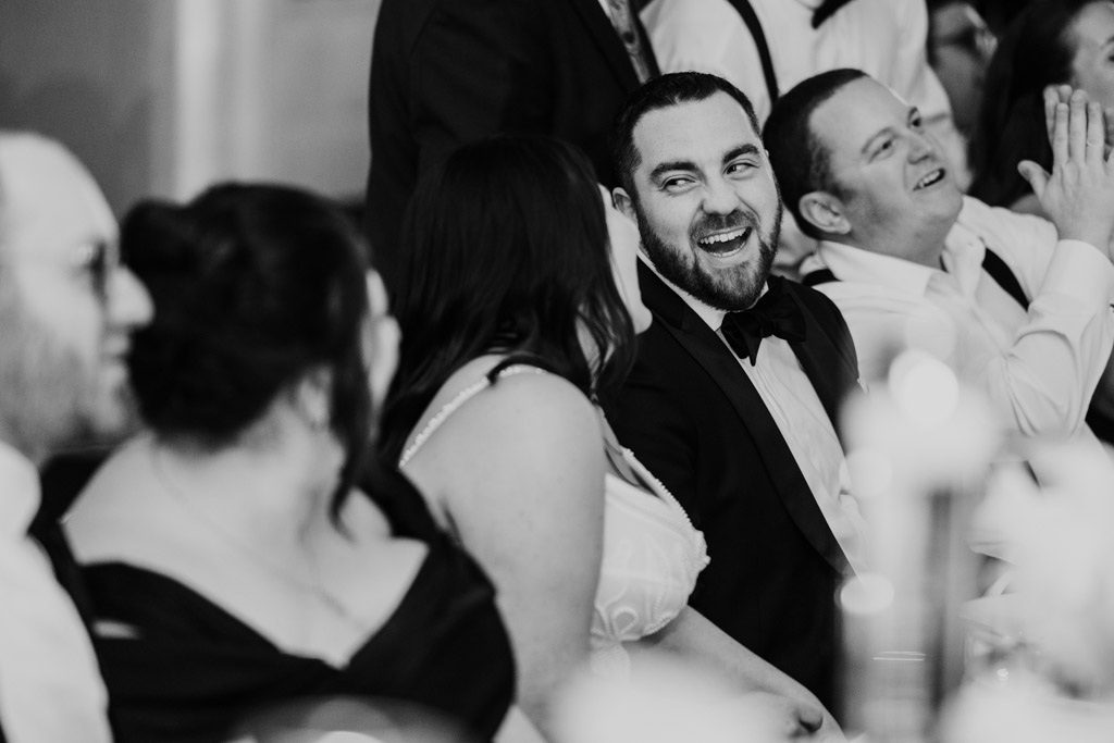 Black and white photo of bride and groom laughing and smiling together during their wedding reception at The Four Seasons Chicago