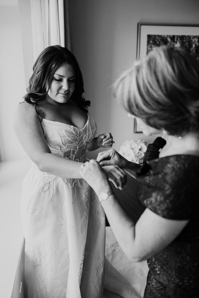 A bride in a wedding dress has her bracelet fastened by her mother while getting ready at The Four Seasons Chicago