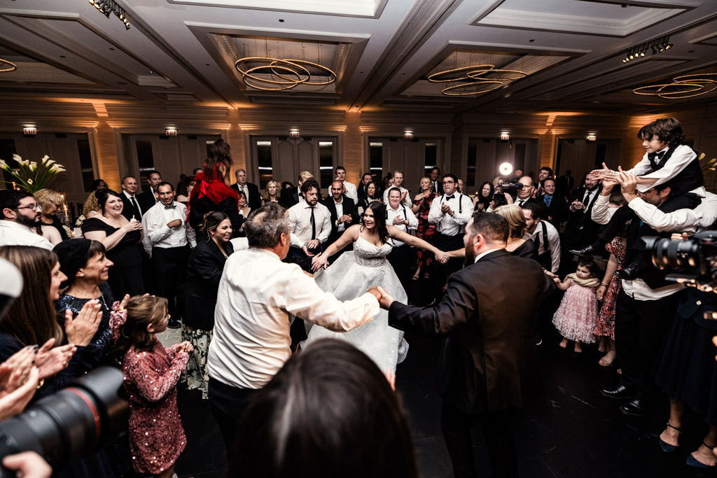 Bride and groom dance with family and friends in a lively circle at a wedding reception at The Four Seasons Chicago
