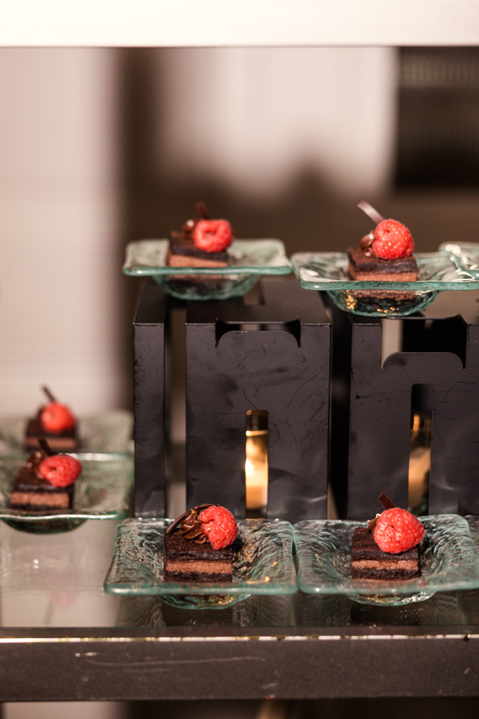 Mini chocolate cakes topped with raspberries, displayed on glass plates with candlelit black stands for wedding reception at The Four Seasons Chicago