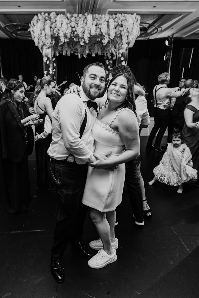 Happy newlywed couple poses together on dance floor during wedding reception at The Four Seasons Chicago, surrounded by other guests