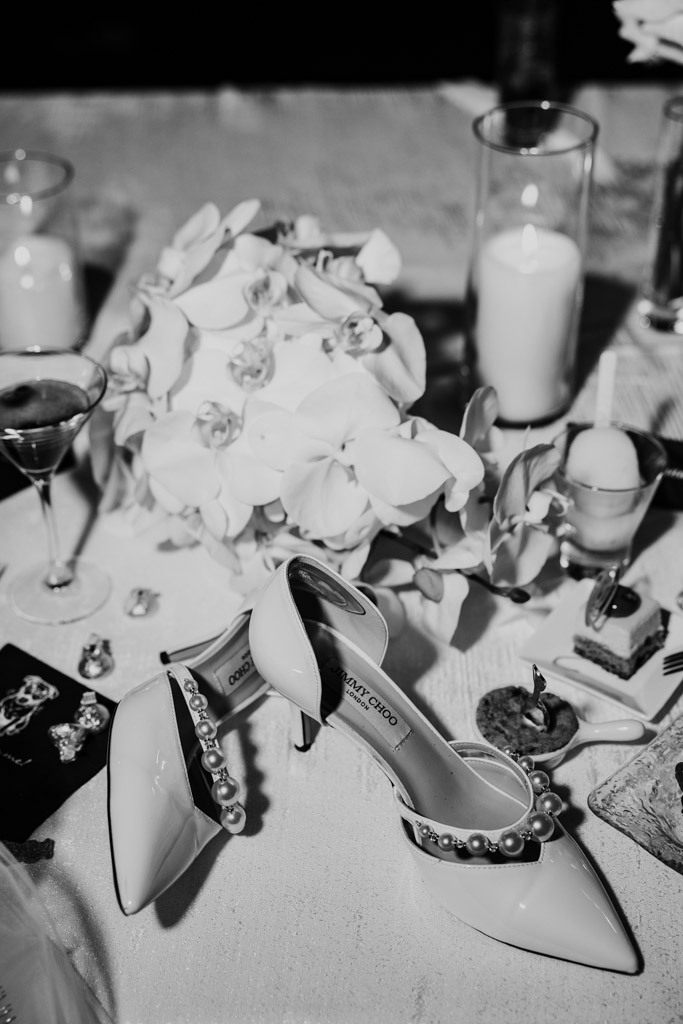 Black and white photo of bride's heels, bouquet, candles, and jewelry arranged on a table at The Four Seasons Chicago