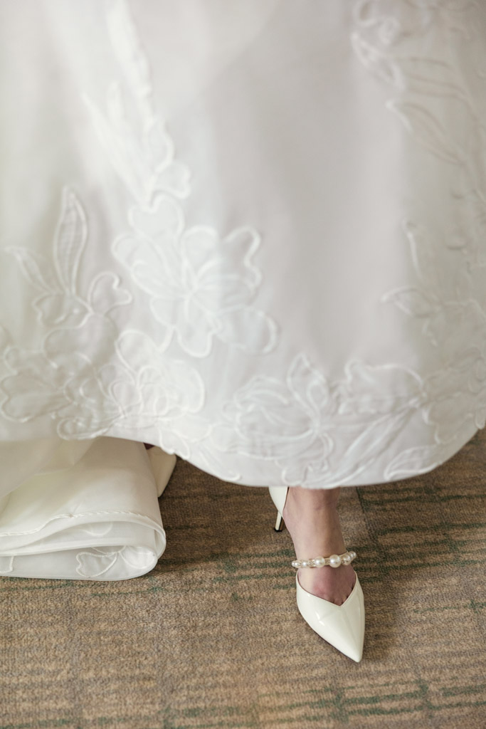 Detail photo of a bride’s white lace dress and pearl-accented white high heels at The Four Seasons Chicago