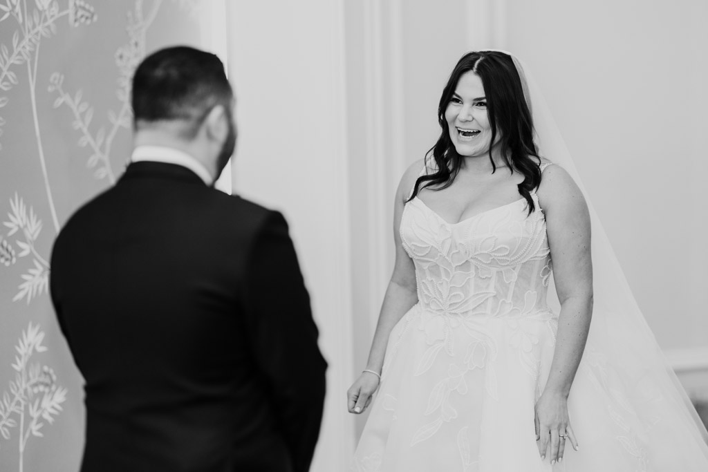 Black and white photo of bride in a wedding dress smiling at groom during their first look at The Four Seasons Chicago