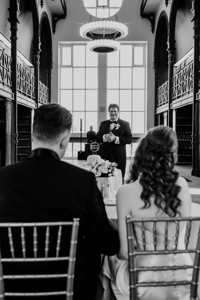 Black and white photo of bride's father giveing a speech to newlywed couple during their Library at 190 wedding reception