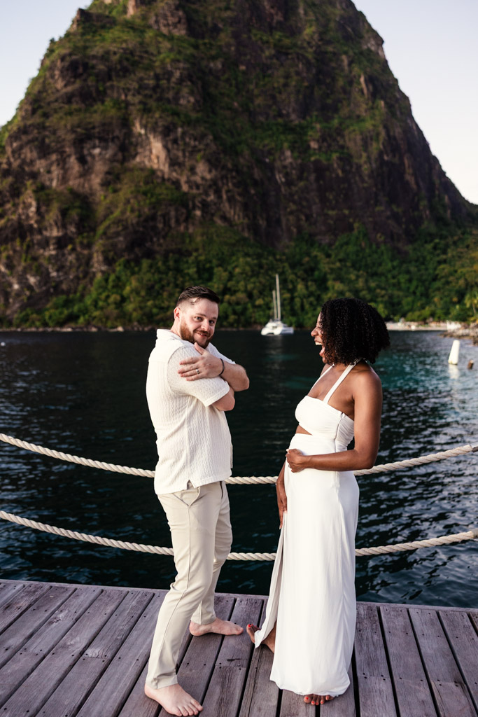 Happy newlywed couple poses barefoot on a dock at Viceroy Sugar Beach, with Petit Piton and sparkling water in the background
