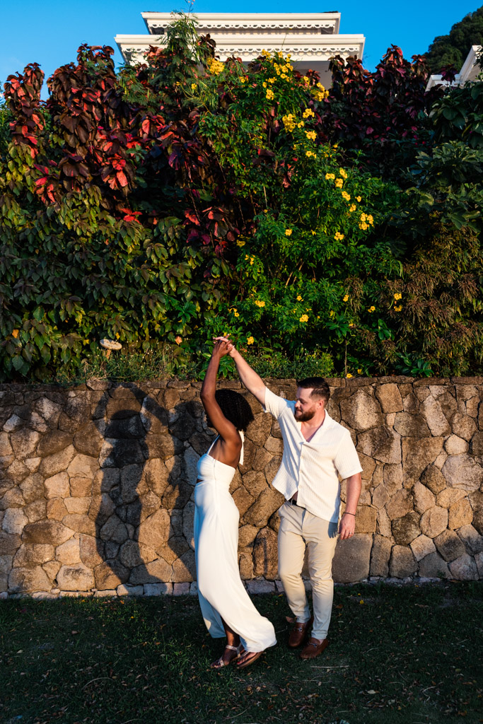 Newlywed couple dances by a stone wall at Viceroy Sugar Beach, surrounded by lush greenery and colorful flowers