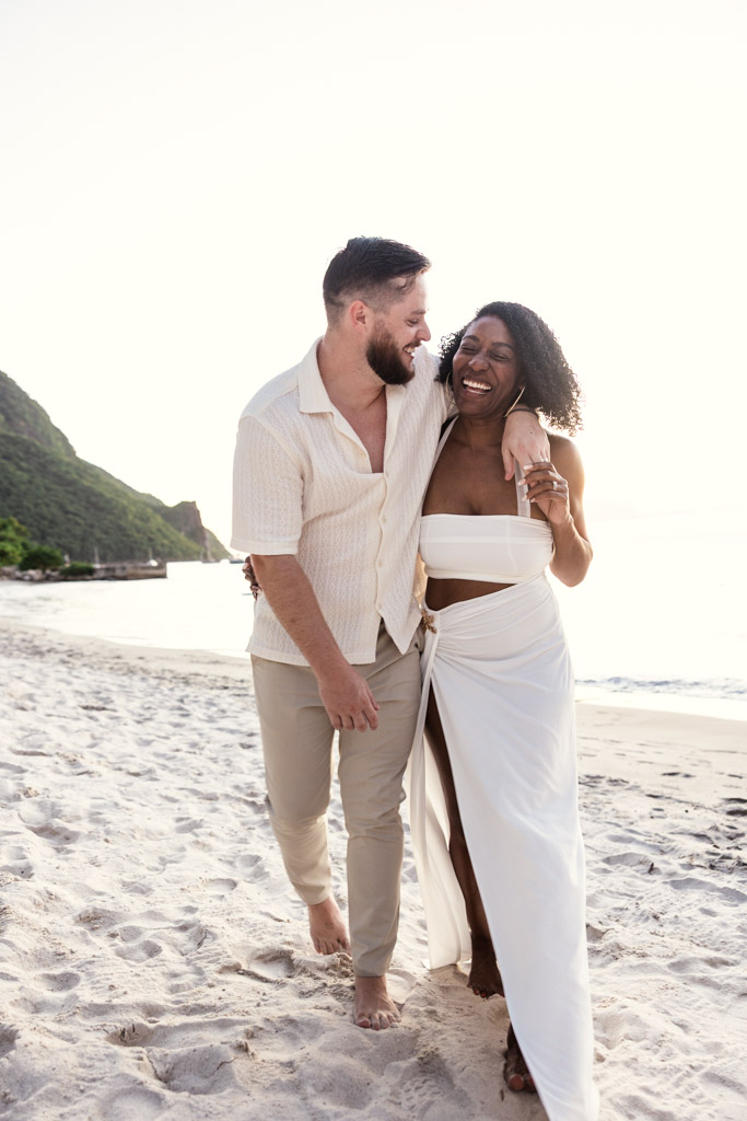 Happy couple walks barefoot on the sand at Viceroy Sugar Beach in St. Lucia