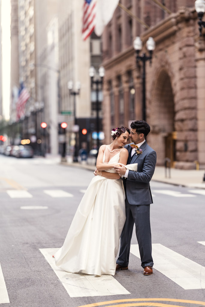 The bride and groom embrace and smile at each other while standing in the middle of a city street during their Wildman BT wedding.