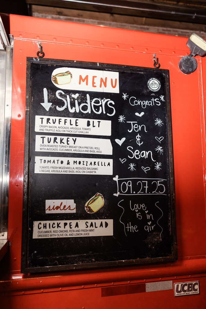 Chalkboard menu on a red food truck with sandwich and salad options, congratulating Jen & Sean on their Wildman BT wedding.