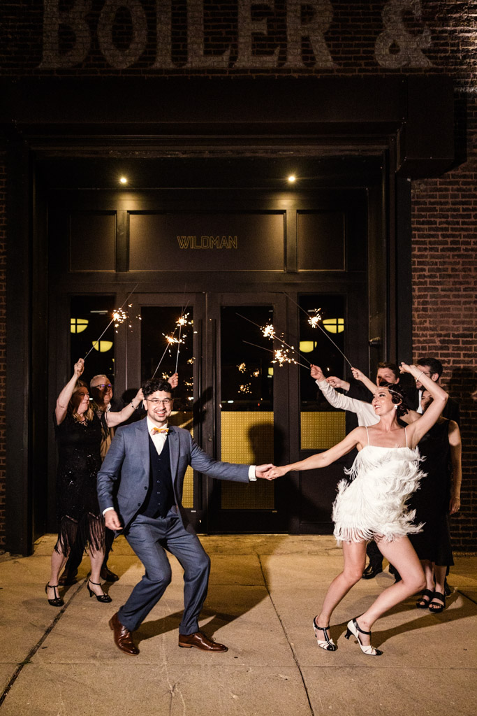 A couple dances outside at night at their Wildman BT wedding, while friends behind them hold sparklers and cheer.