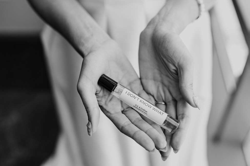 Black and white photo of hands holding a perfume bottle labeled 