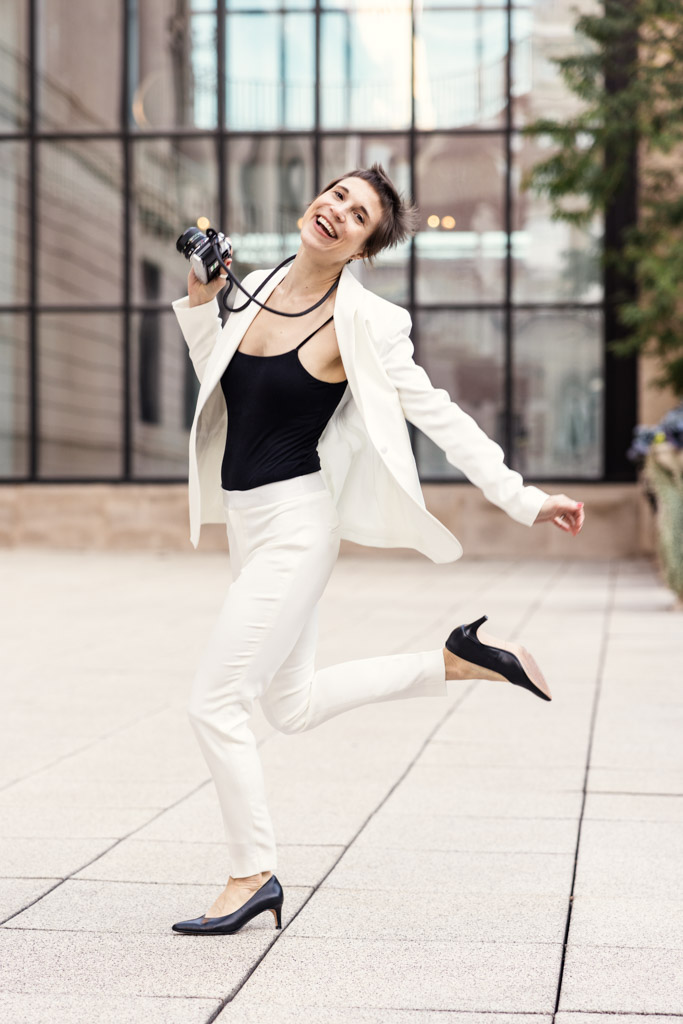 A Chicago wedding photographer in a white suit holds a camera, ready to capture unforgettable moments.