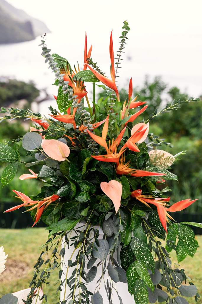 A vibrant floral arrangement with orange tropical flowers and lush green leaves for Viceroy Sugar Beach wedding ceremony