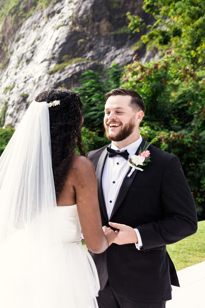 Bride and groom smile at each other outdoors, holding hands during wedding ceremony at Viceroy Sugar Beach