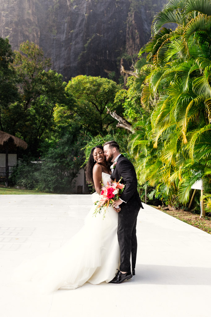 A bride and groom smile and embrace outdoors at Viceroy Sugar Beach's wedding ceremony space