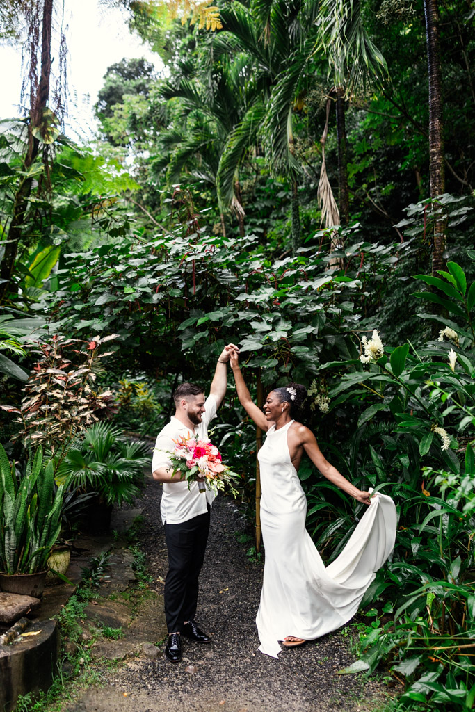 Newlywed couple dances joyfully in Diamond Falls Botanical Gardens, the bride holding her dress and the groom holding her bouquet