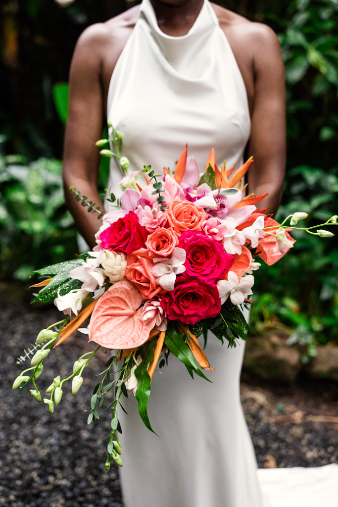 Detail photo of bride's vibrant bouquet of pink, orange, and white flowers outdoors at Diamond Falls Botanical Gardens
