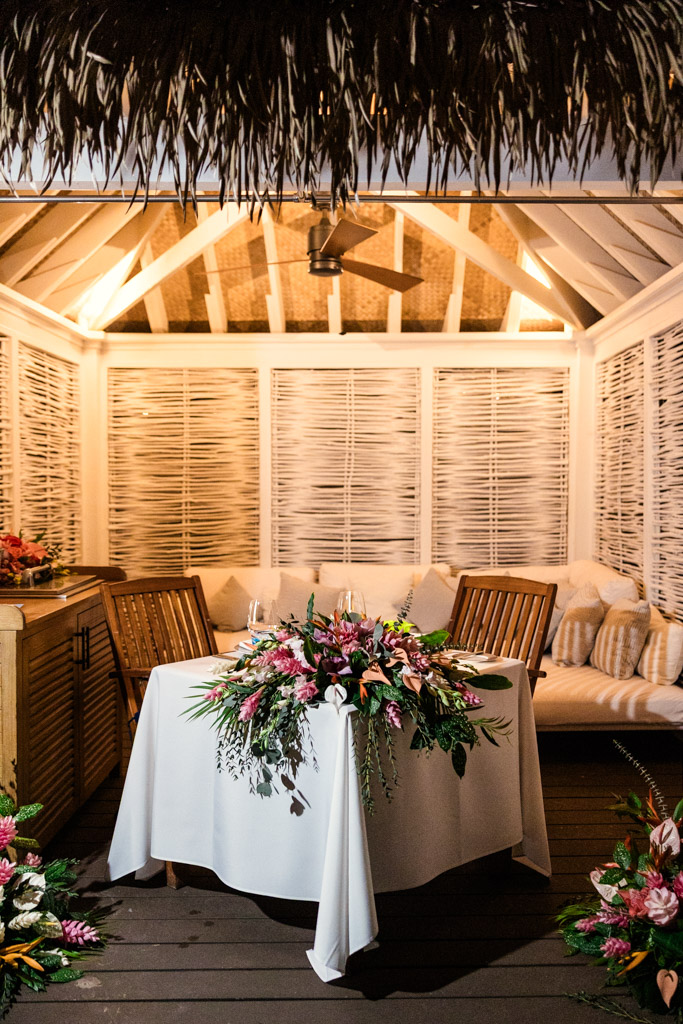 Sweetheart table with flowers and wine glasses in a cozy, softly lit gazebo at Viceroy Sugar Beach