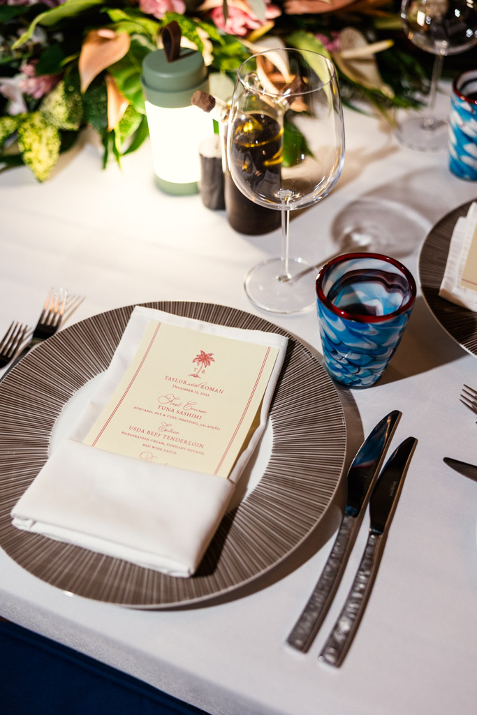 A formal place setting at Viceroy Sugar Beach features a menu on a plate, glassware, silverware, and floral centerpiece