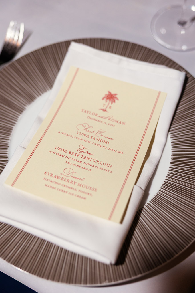 A printed dinner menu rests on a white napkin atop a decorative plate at a formal Viceroy Sugar Beach table setting