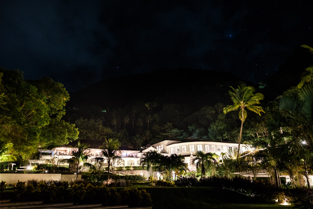 Viceroy Sugar Beach resort at night, surrounded by palm trees with a dark hillside and starry sky in the background