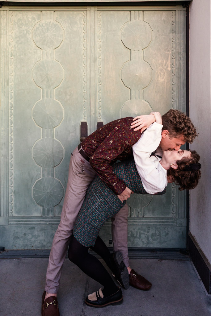 A couple kisses as one dips the other in front of a light green door at Griffith Park Observatory in Los Angeles