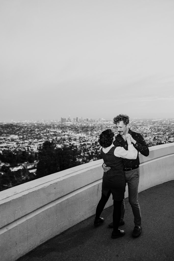 Black and white photo of couple dances together on a terrace at Griffith Park Observatory overlooking Los Angeles