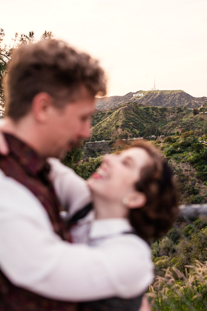 Creative photo of blurred couple embracing and smiling, with the Hollywood sign visible in the background
