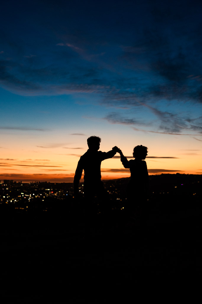Silhouettes of two people dancing at sunset with Los Angeles cityscape and colorful sky in the background