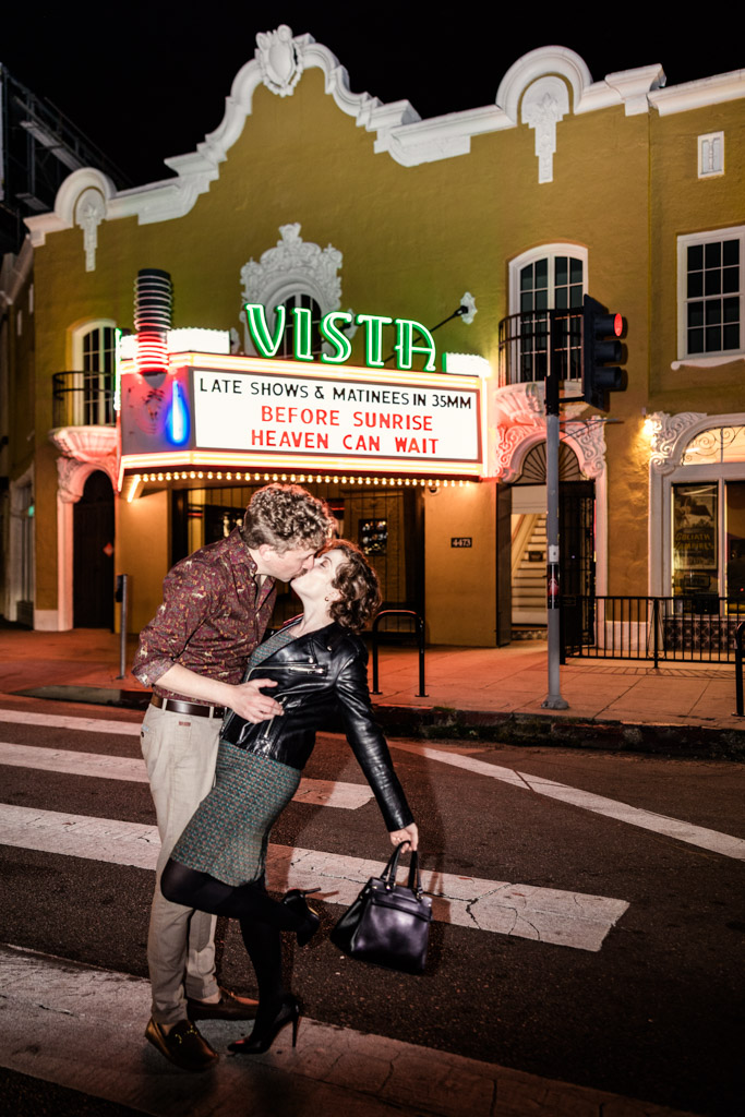 Engaged couple kisses at night in front of a lit-up Vista Theatre marquee