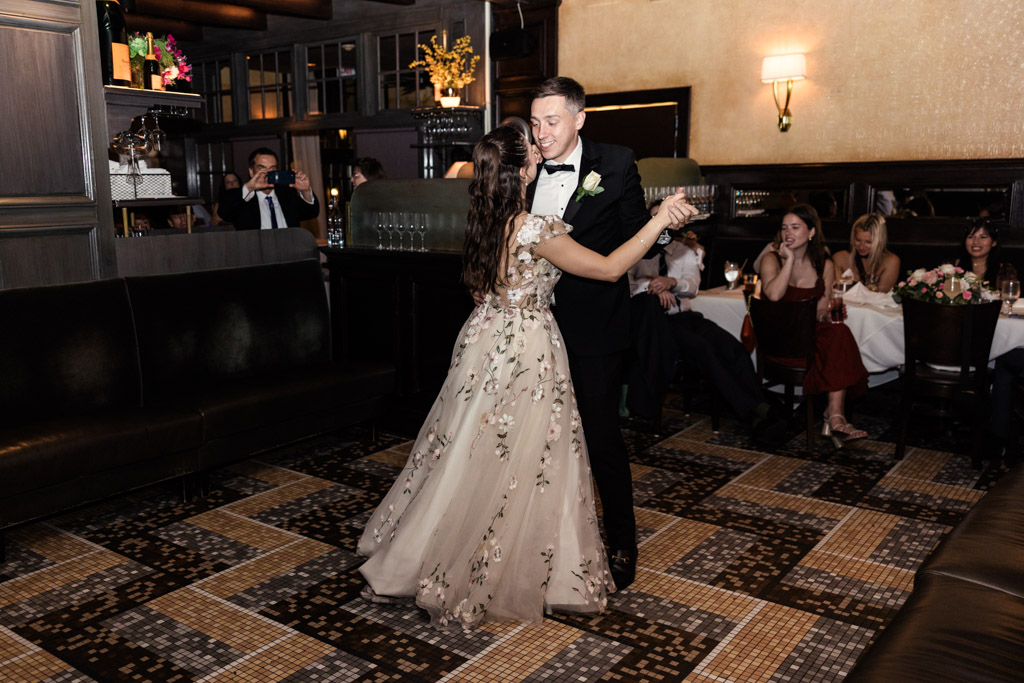 Bride and groom share their first dance inside Mon Ami Gabi restaurant, with guests watching