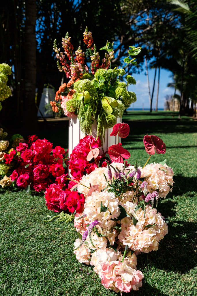 Colorful flower arrangements on green grass with a sunny outdoor background and palm trees for a Frente al Punto wedding