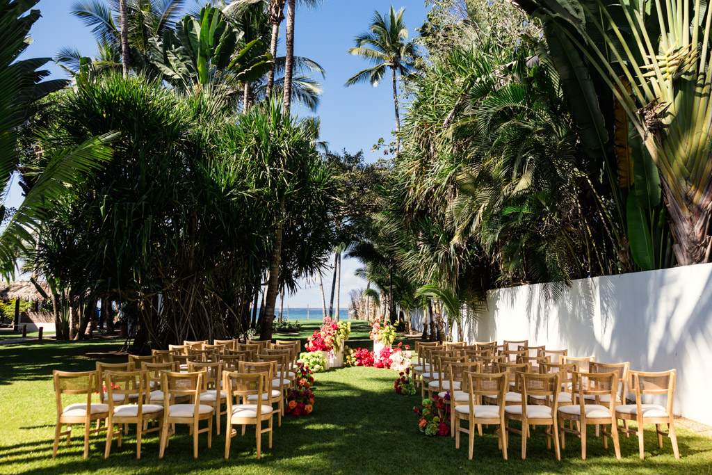 Frente al Punto wedding ceremony space with wooden chairs and colorful floral arrangements, surrounded by lush tropical trees
