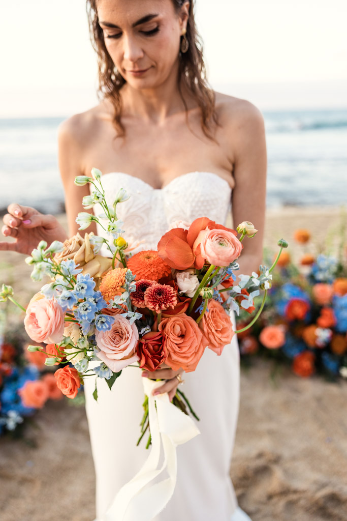Detail photo of colorful bouquet of flowers held by bride in a strapless white dress